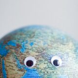 earth globe with googly eyes on gray background