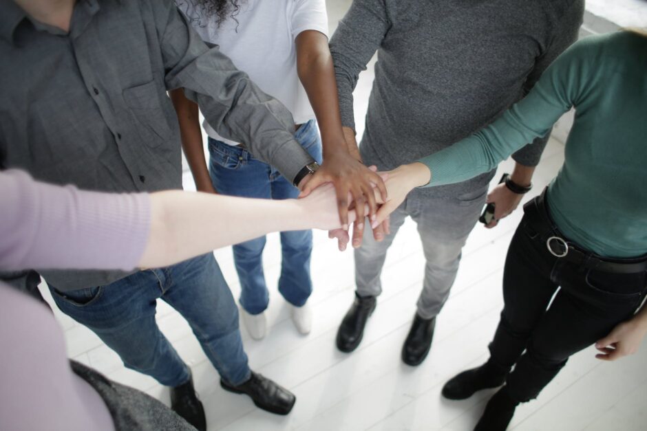 crop multiracial people joining hands together during break in modern workplace
